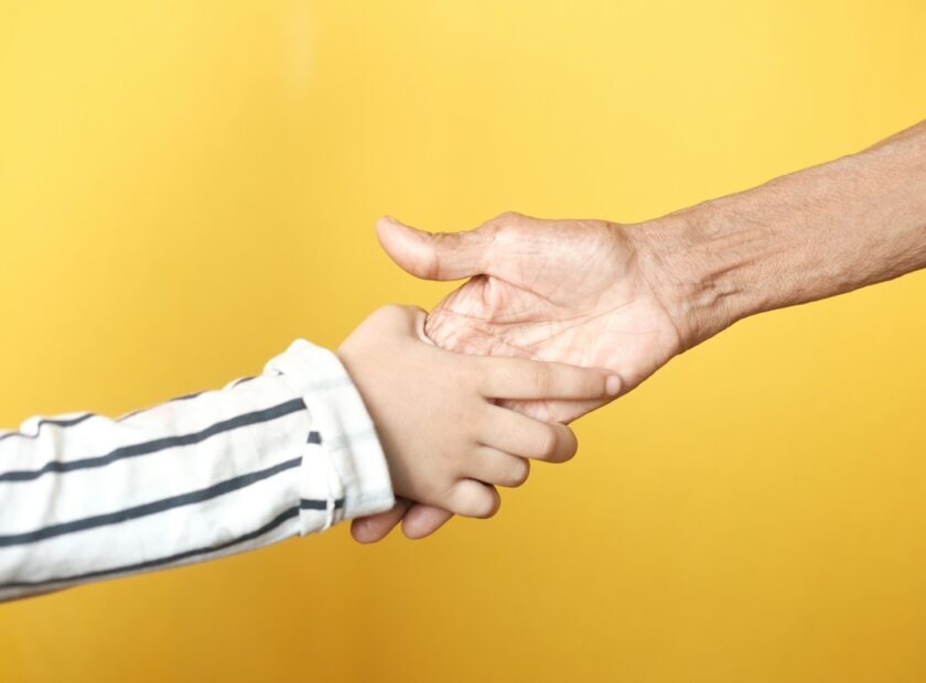 a person holding a child's hand with a yellow background