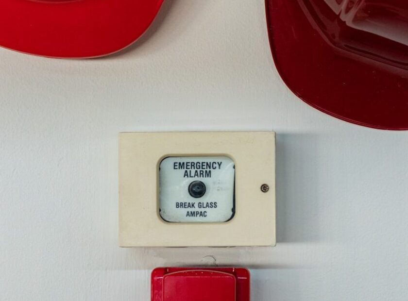 two red hard hats near emergency alarm button