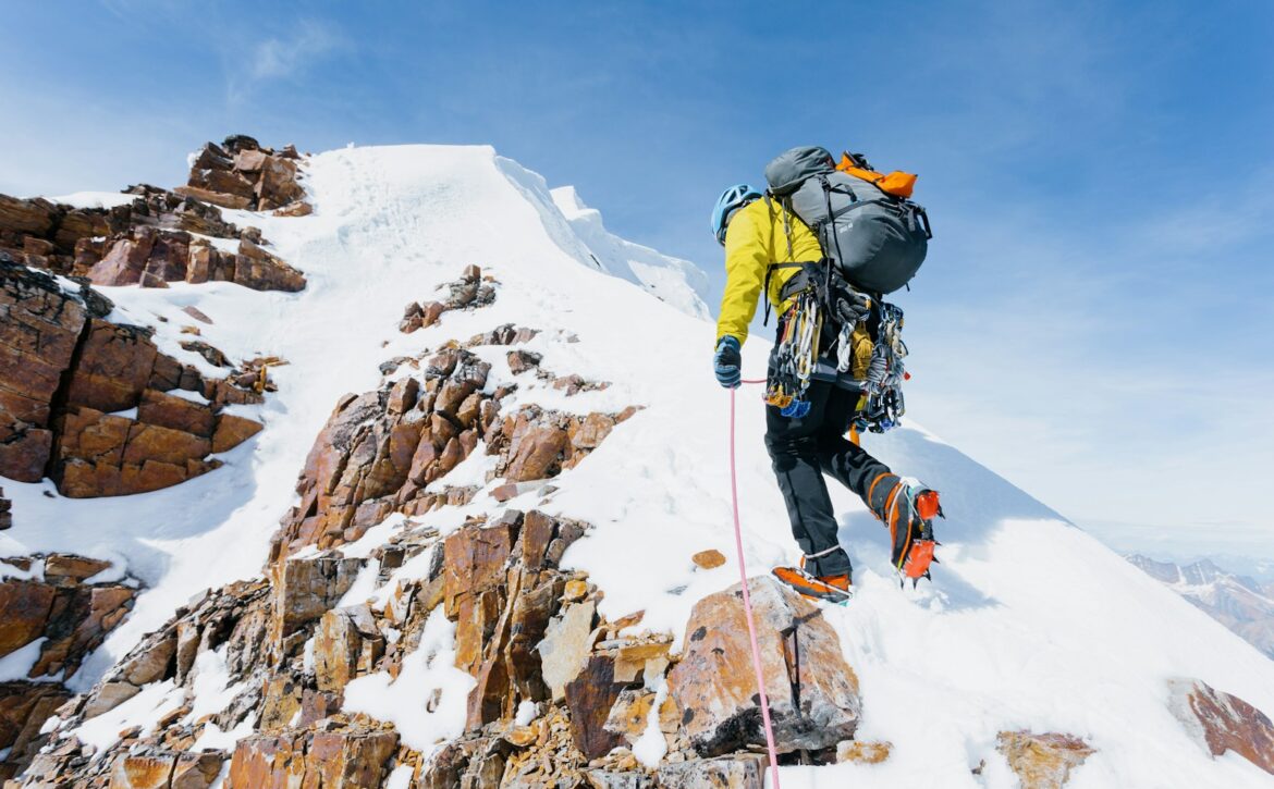 a man climbing up the side of a snow covered mountain