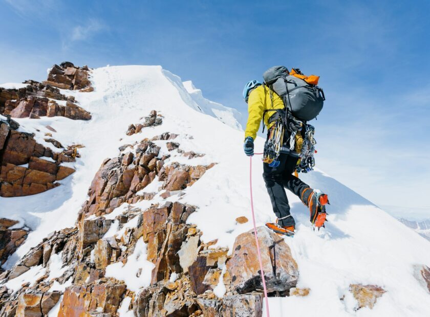 a man climbing up the side of a snow covered mountain