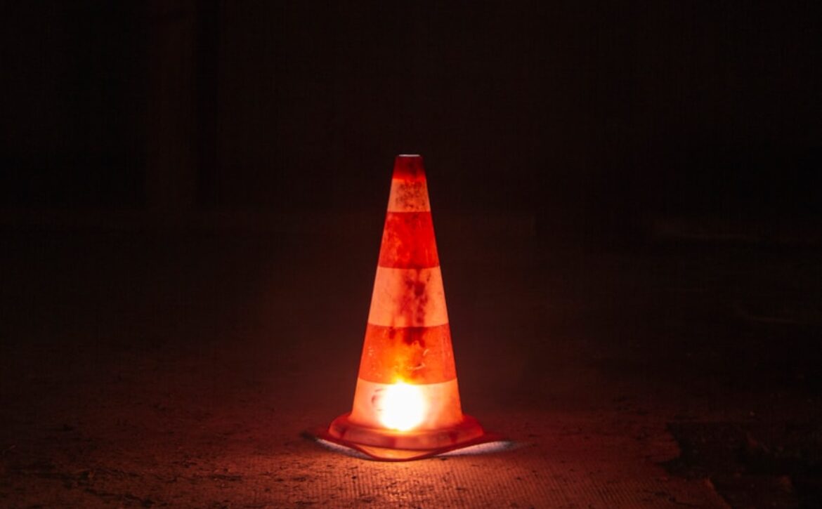 A traffic cone sitting on the ground at night