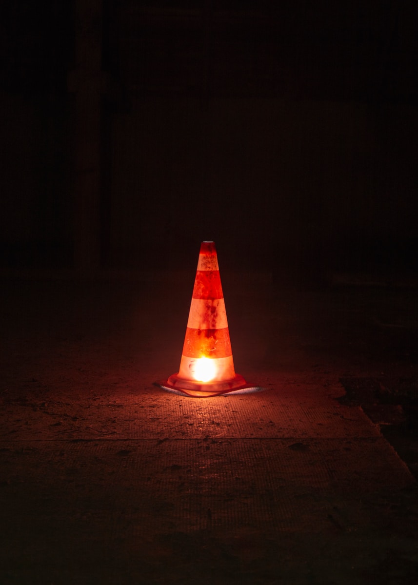 A traffic cone sitting on the ground at night