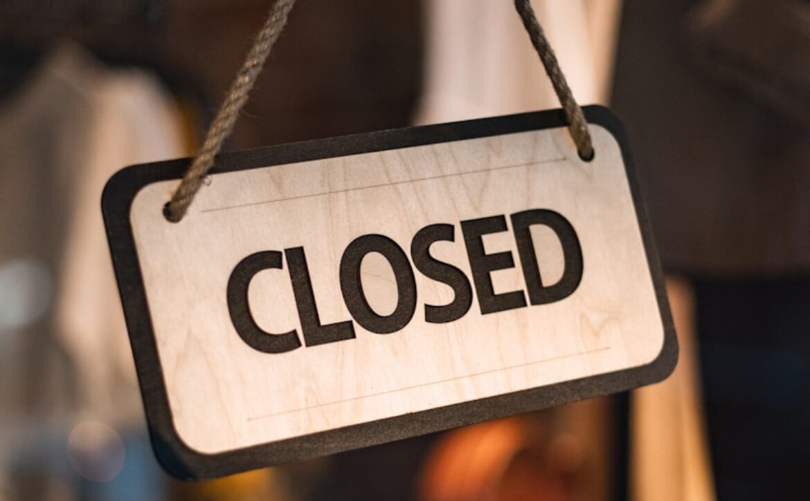 A close up of a closed sign hanging from a rope