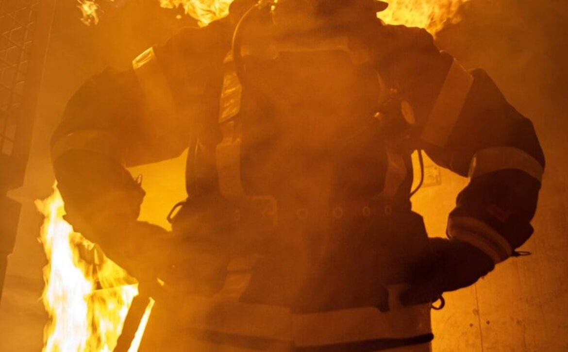 a firefighter standing in front of a large fire