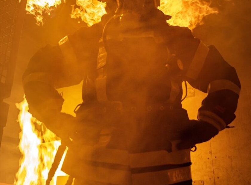 a firefighter standing in front of a large fire